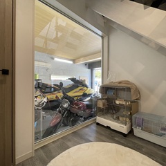 室内からバイクが鑑賞できるインナーガレージ。ガラス仕切りで明るく開放感がある空間設計。収納スペースも有効活用されている。