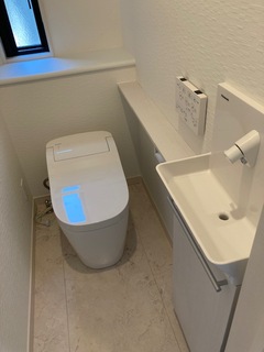コンパクトで機能的なトイレ空間。シンプルなデザインで清潔感があり、使いやすさが考慮されている。手洗い器も設置されている。
