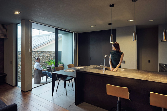 「GRAFTEKT」のキッチンとダイニングテーブルを並べて配置したダイニングキッチン。ダイニングの先にテラスが設けてあり、晴れた日には外で食事を楽しむこともできる