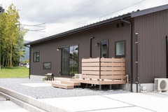 シンプルでモダンな外観の住宅。勝手口の木製のフェンスとデッキが特徴的で、プライベートな空間が確保されている。【ビビットホーム（アクティス）】