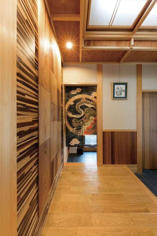 玄関ホールは、ヒノキ柱にケヤキの折り上げ天井…と木組みを現した贅沢なつくり。アーティスティックな壁は、秋田スギとローズウッドをそれぞれ特殊加工したもの