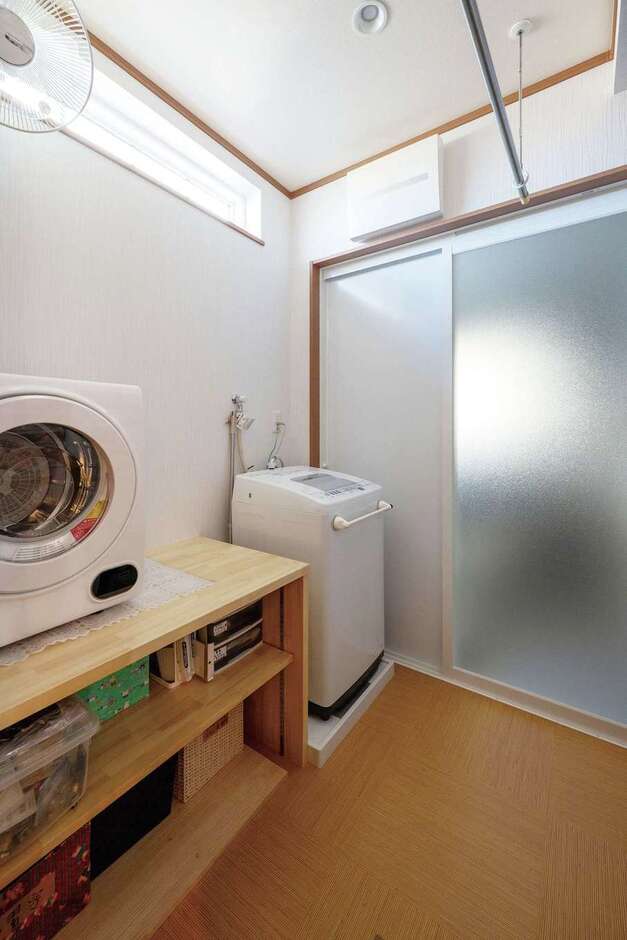 二世帯共有の脱衣兼ランドリールームと浴室。収納棚は造作で。場所を取らない衣類乾燥機も重宝している