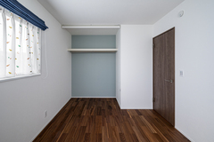 シンプルで落ち着いた雰囲気の子ども部屋。窓から自然光が差し込み、明るい空間が広がる。壁に取り付けられた棚は収納に便利で、使いやすさも考慮されている。【トキワハウス デザイン アンド ビルド（常盤工業）】