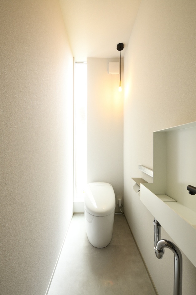 シンプルでスタイリッシュなデザインのトイレ空間。スリムな形が特徴で、ナチュラルな光が差し込む明るい雰囲気である。