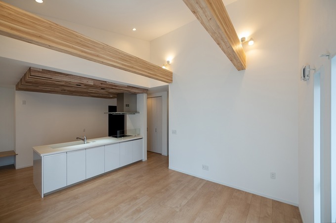 最も長い時間を過ごすリビングは、勾配天井で解放感を。化粧梁にキッチンの折下げ天井が、空間を引き締めるアクセントに