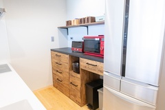 温かみのある木製の引き出しとカウンターが特徴のキッチン。電子レンジやトースターをスッキリと収納し、機能性を重視したデザイン。