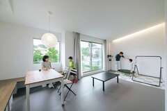 グレージュを基調としたリビングダイニングは間接照明だけでシンプルに。床は店舗でよく用いられるSフロアで、お手入れも簡単。ゆるやかな勾配天井が、断熱・気密効果を損なわずに開放感を添える