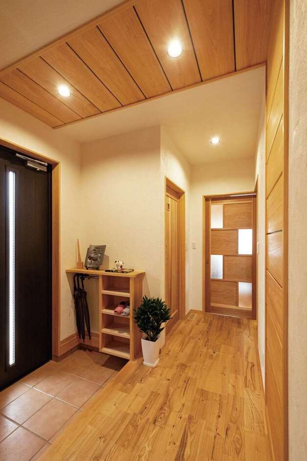 玄関ホールの天井から壁に続く木を使った意匠は、モデルハウスをお手本に。スリッパラックと傘掛け収納は造作で