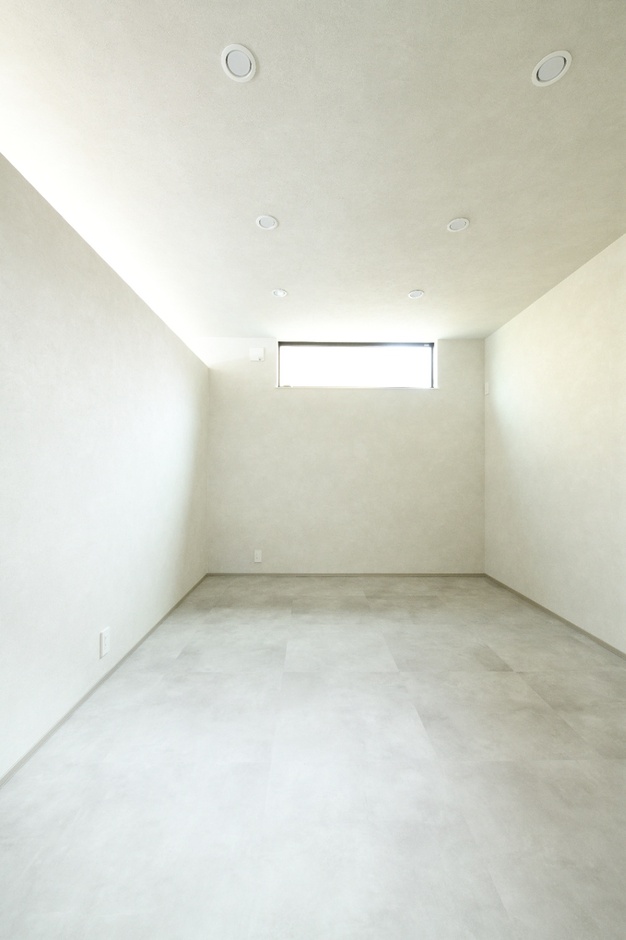 シンプルでミニマルなデザインの居室。小さな窓から自然光が入り込み、落ち着いた雰囲気を演出している。