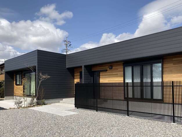 広い敷地を活かして建てた平屋の外観。黒いガルバリウム鋼板の外壁に、レッドシダーの板張りの壁を組み合わせてアクセントをつけた