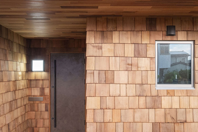 玄関ポーチの壁にもリビングと同じシダーシェイクを採用。軒天は一般的なレッドシダーで引き締めた