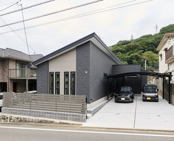 片流れ屋根が特徴的なモダンな外観の平屋。シックな色合いの外壁と広々としたカーポートが、落ち着いた印象を与えるデザイン。