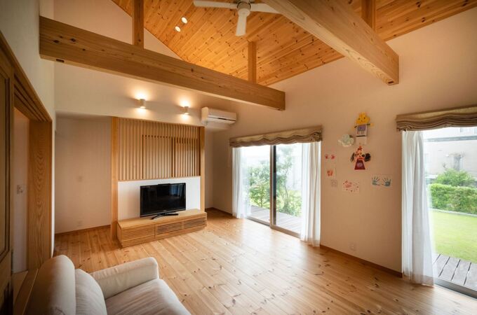 大きな開口部から庭を眺めながら過ごせるリビング。天井の羽目板と南北に走る太い梁が安心感を与える。テレビ背面の格子がアクセントに