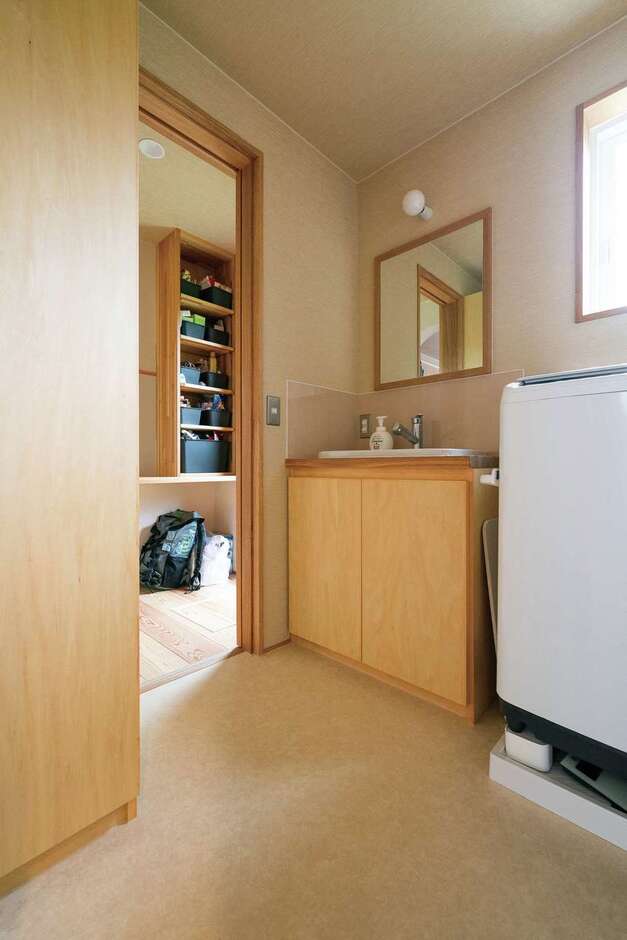 木製の洗面台は造作仕上げ。奥のパントリー、キッチンへとつながる動線が便利
