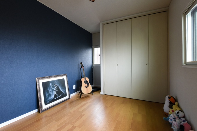 壁にアクセントクロスが施された子ども部屋。フローリングが明るく、自然光が差し込む窓があり、開放感が感じられる空間である。
