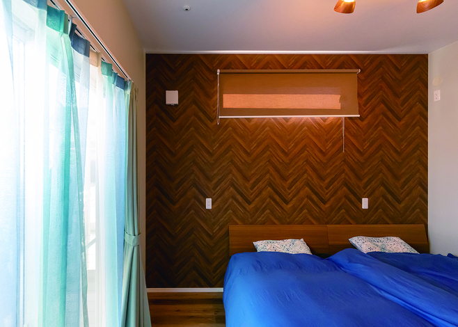 リゾートホテルのようなヘリンボーンの壁が印象的な寝室。将来を見据えて1階に設計