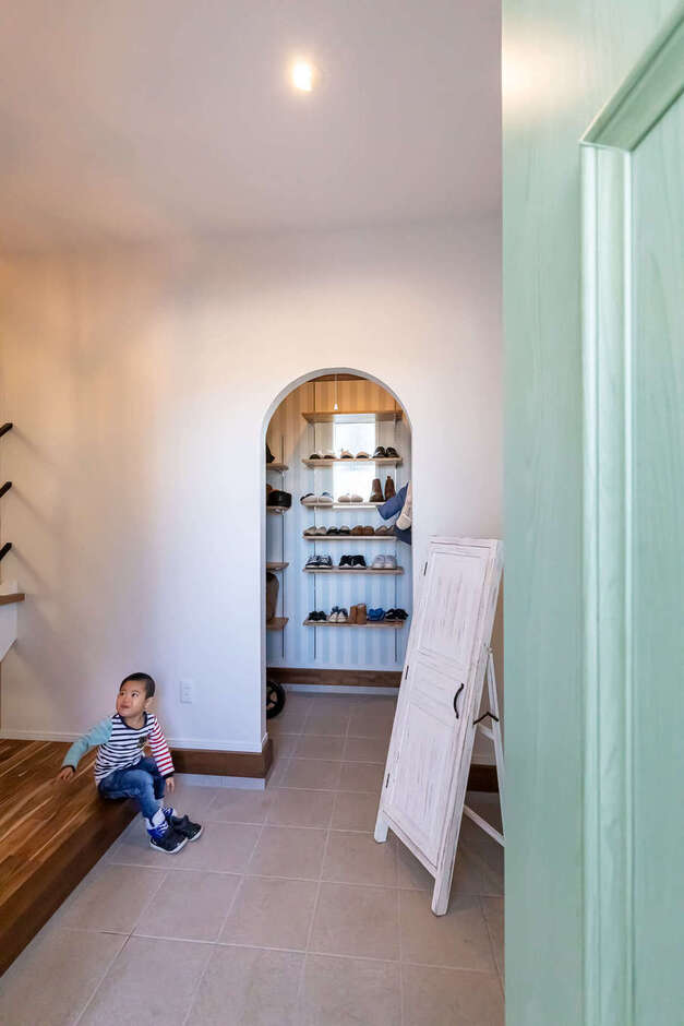 ゆったり広々の玄関ホール。アーチ型にくり抜いた玄関クローゼットは、アウトドアグッズもすっぽり収まるほど広い。おしゃれな鏡を見ながら、元美容師のご主人が子どもの髪の毛をカットすることも