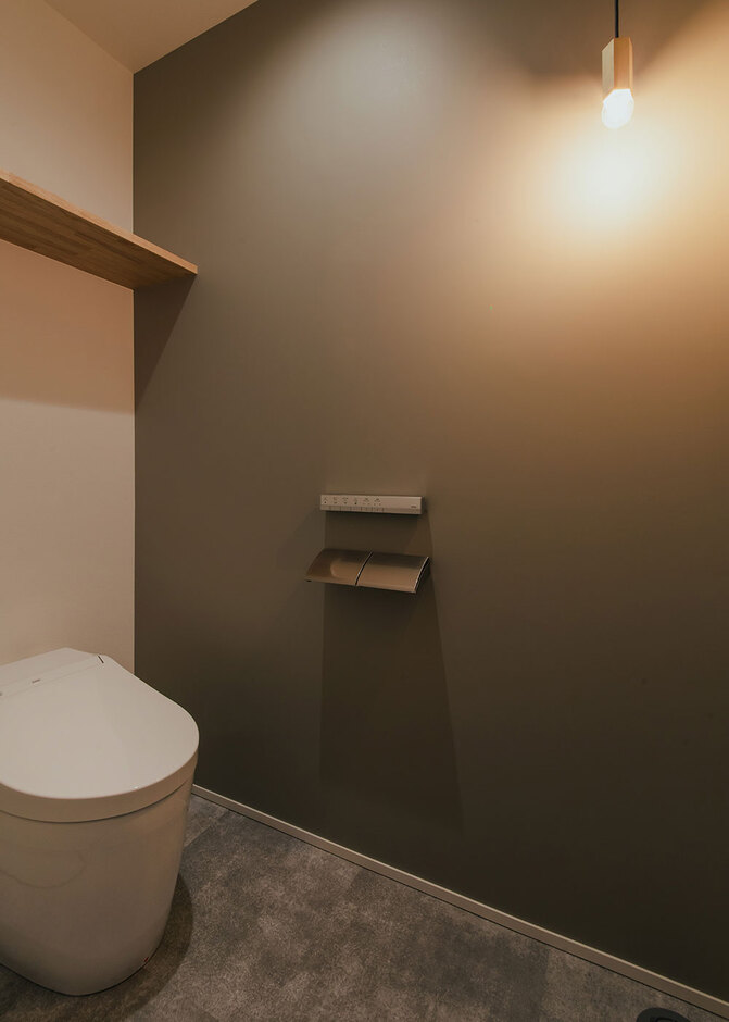 フォーカルポイントに印象的なペンダントライトを配したトイレ空間はクロスもアクセントになる色をチョイス。細かな場所にもKさん夫妻のセンスが感じられる