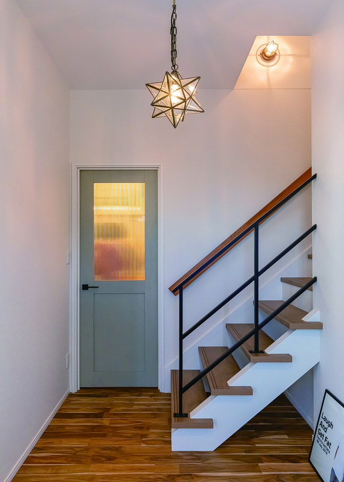 色味が可愛らしい建具や無垢材の床、アイアンの階段手すり、ブラケットライトなど、各所にこだわりが見られる。星形のペンダントライトが空間をまとめている