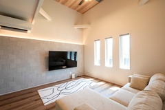 高い天井と大きな窓が開放感をもたらすリビング。壁のアクセントが空間にモダンなエレメントを追加する。