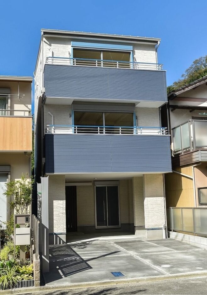 モダンなデザインの3階建住宅の外観。ホワイトをベースにブルーグレーのツートンカラー。