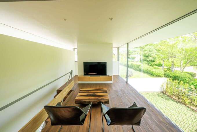 2階に上がると目を見張るほどの開放感あふれるリビングに。ガラス越しの豊かな緑と杉の無垢床が温かく迎え入れる。TVボードの背面は個室として対応できる空間が用意されている