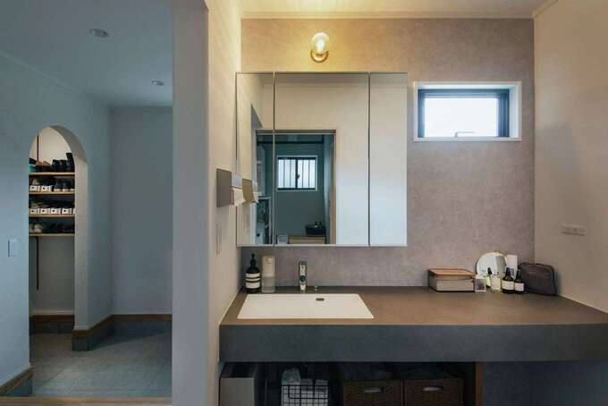 玄関から直結する手洗いコーナー。スタイリッシュな洗面台は造作で。身長が高いご主人もストレスなく使えるようワークトップを高めに設定。壁の出隅がすべてRになっているので、小さな子どもも安全