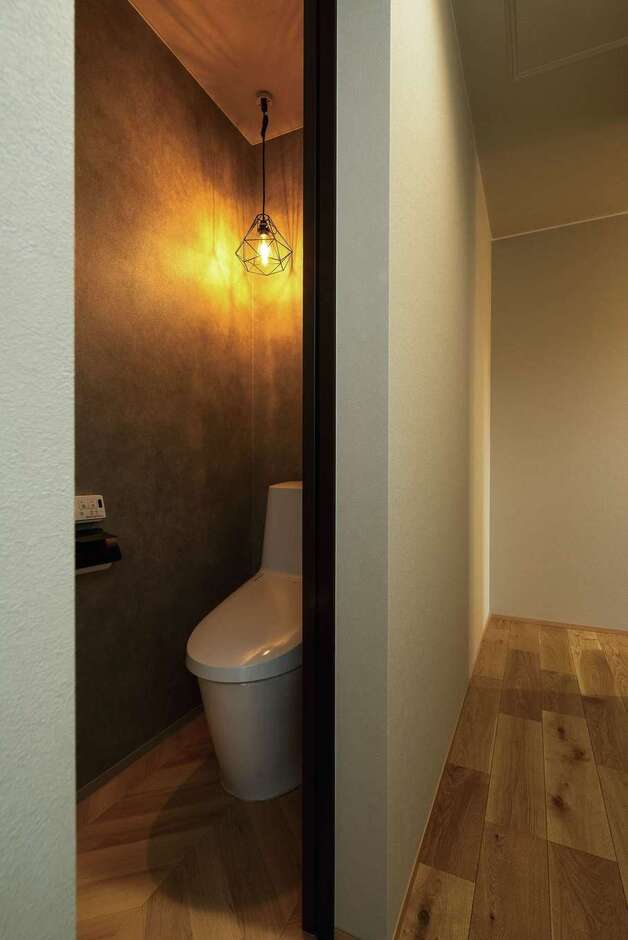 トイレは濃いグレーのクロスと暖かな照明で、ほっと落ち着く空間に。ニッチのペーパー置き場が用意されている