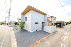 シンプルでモダンなデザインの住宅外観。明るい外壁と木製の屋根が調和し、周囲の風景とよく馴染んでいる。【モデスト】