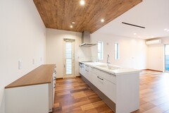床の色と合わせて、キッチンの下がり天井にも木目調のクロスを使用。
天井にはアクセントをつけることで、キッチンをグッとおしゃれに見せてくれます。【丸宗建設】