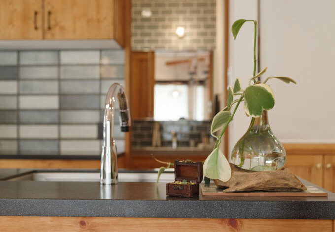 ちょっとした観葉植物がよく似合う、アイランド型のオープンキッチン。壁面にはブルーのタイルがセンスよくあしらわれている