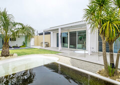 ガーデンに設けた池から見た住空間。南国の木々が似合う、リゾートライクな平屋建てを実現した