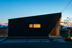 夜の美しさが際立つシンプルで洗練された建物の外観。控えめなライトが建物の形状を際立たせ、落ち着いた印象を与えている。