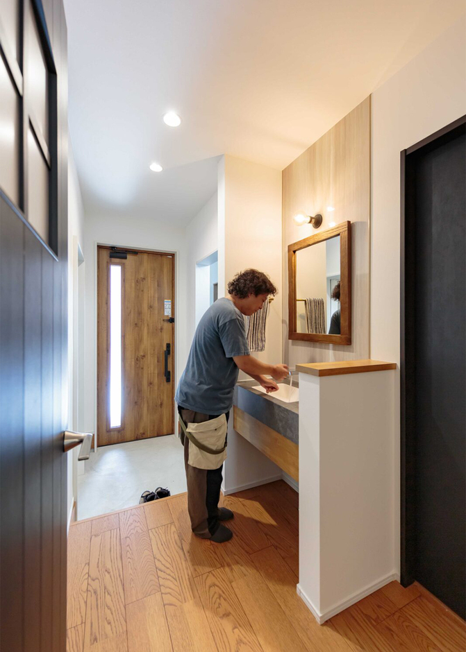 土間クローク付きの玄関を上がると、造作洗面台とトイレが隣接する動線が暮らしに便利。洗面台にはコンクリート調のカウンターを使うなど、家全体のデザインテイストを統一している