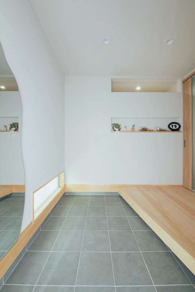 玄関に足を踏み入れると、ヒノキの香りが迎えてくれる。窓は隣家との関係に配慮して計画。ニッチ上部の開口は、洗面室に光を届けている
