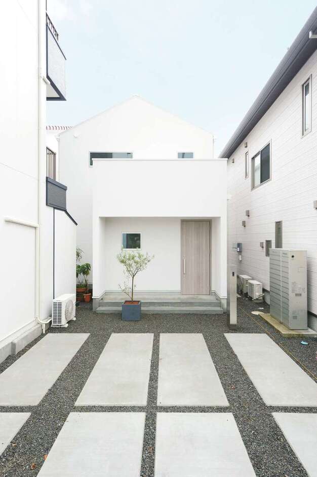 屋根も外壁も白を採用した外観。三角屋根と四角いファサードの対比が美しい。約50坪の細長い土地形状を上手に活かして、風通しと採光を確保した
