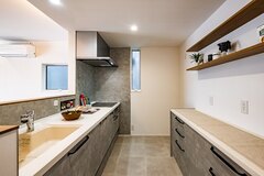 グレーを基調とした、シンプルで使い勝手の良いキッチン。背面の食器棚はカウンタータイプで十分な収納スペースを確保しつつ、上部の飾り棚がデザイン性を高めてくれている。【DAIBA HOME】