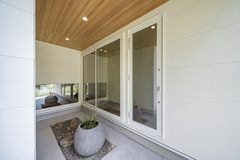 シンプルで洗練されたスペース。大きなガラスドアと自然素材の天井が、モダンな雰囲気を演出している。庭の景色が楽しめる心地よい空間。