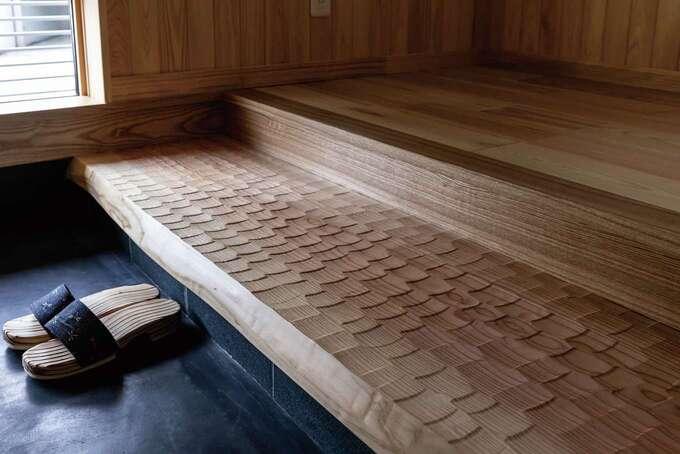 玄関の式台には、一枚板の青森スギを使用。職人が手仕事で仕上げた表面のなぐり加工は、見た目の美しさに加え、足触りの良さを高める効果も