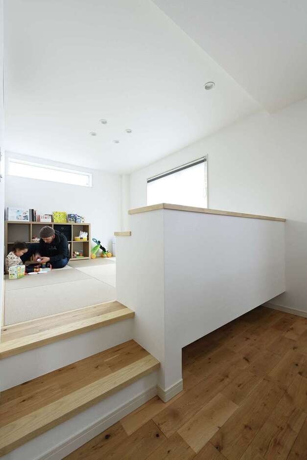 リビングの隣に階段付きの小上がりを設置。仕切壁の下をオープンにしてロボット掃除機が通れるように工夫されている。小上がりはキッズコーナーとして利用可能。おもちゃがリビングまで広がらずに済むので、LDKをスッキリ・キレイに保てる