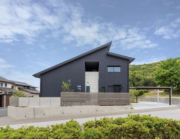 アシメトリーな屋根が個性的な外観。中央のレンガ調の外壁の上部にはサービスバルコニーがある。カーポートや門扉のデザインまでこだわり、建物と外構をトータルでコーディネート