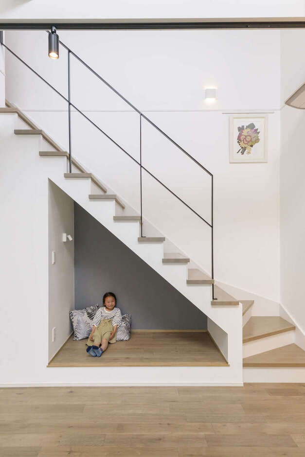 リビング階段下のスペースを活かしてつくったヌック。座れば、視線の先に青空や緑の庭が見えて、ホッと癒やされる。シャープなラインの手すりと木の階段の組み合わせはアートのように美しく、友人からも大好評だそう