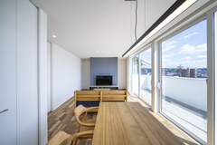 大きな窓から光が差し込むリビングダイニング。明るい空間と開放感があり、窓外の眺めも楽しめる。家具の配置が居心地の良さを引き立てている。