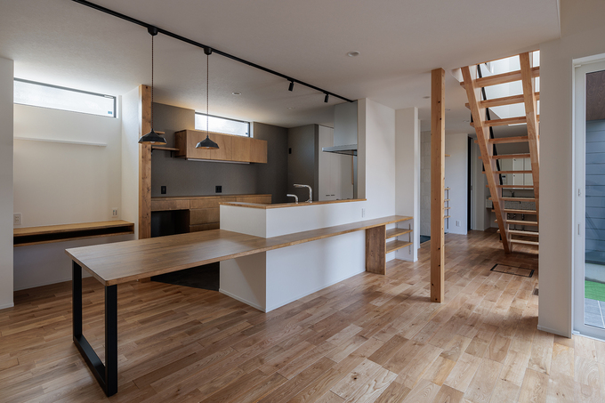 開放感のあるキッチン。木の温もりを感じる無垢フローリングと白いカウンターが、スタイリッシュな雰囲気をもたらす