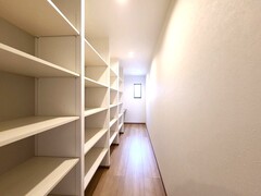 縦長５帖のパントリーに、壁いっぱい可動棚を設置。自然光が差し込む明るい空間で収納力は抜群。