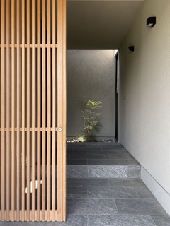 薄暗くなる北側玄関にはやさしい光が降り注ぐ光庭を配置。木格子建具が進むアプローチを演出し防犯上にも配慮している。【安田住宅｜安田建築設計室】