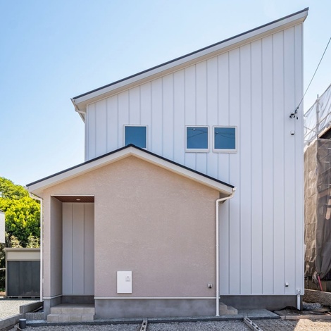シンプルな屋根のラインと窓の配置が特徴的で、全体的にスッキリとした印象を与える。ガルバリウムと塗り壁を組み合わせ、デザイン性とナチュラルで温かみのある印象