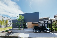 台形の変形地に建てたH邸。ブラックのガルバリウムと木調の壁が絶妙のバランスで融合し、美しい佇まいを見せている。洋の外観とアカマツ・紅葉といった和の植栽とのコントラストに建築家のセンスを感じる【ハウスコネクト】