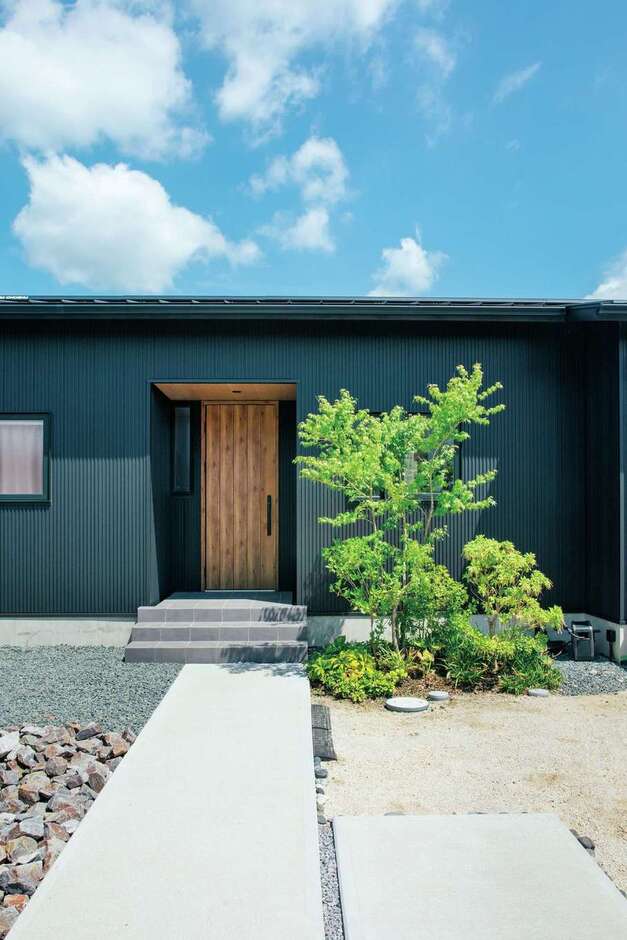 屋根と外壁は、耐久性の高いガルバリウム鋼板をセレクト。木製ドアとシンボルツリーがほど良いアクセントに