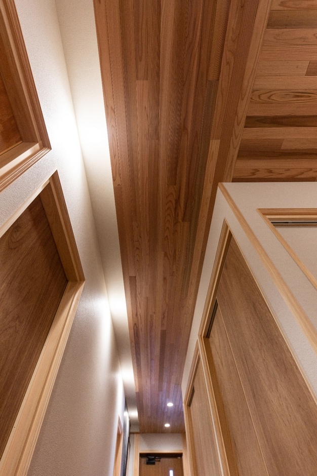 赤身のスギ板の木目が美しい天井と手づくり引戸が特徴の廊下空間。温かみのあるデザインで、家庭内に落ち着いた雰囲気をもたらす。